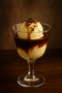 Copa elegante con helado de vainilla cubierto de Pedro Ximénez y virutas de chocolate negro, servido como postre-cóctel típico de Jerez.